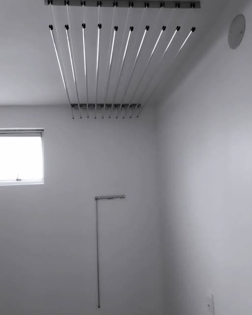 Varal de teto visto de baixo, com as varetas penduradas e a corda descendo pela parede